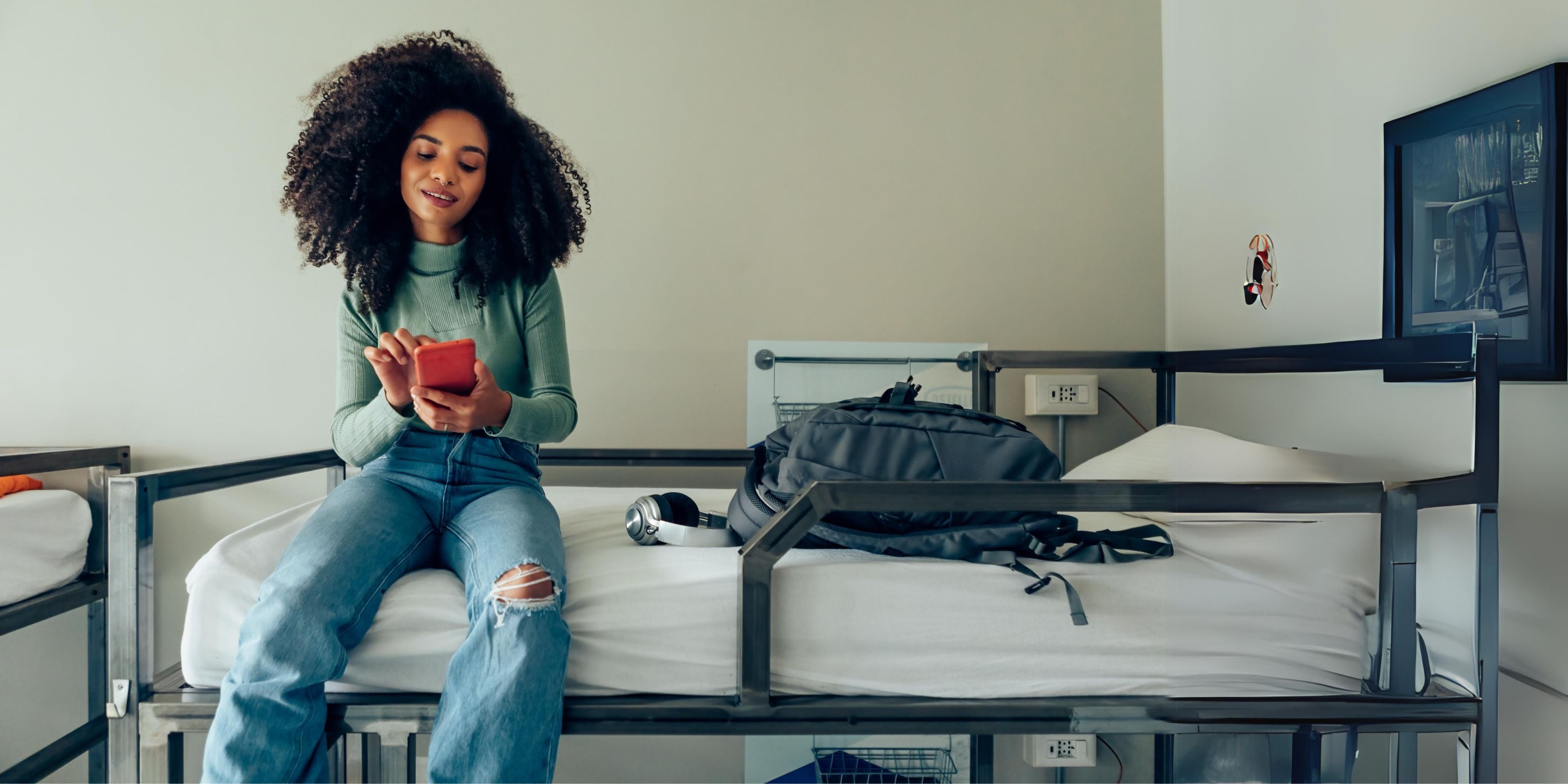 College student sits on bunk bed texting with comfortable mattress topper