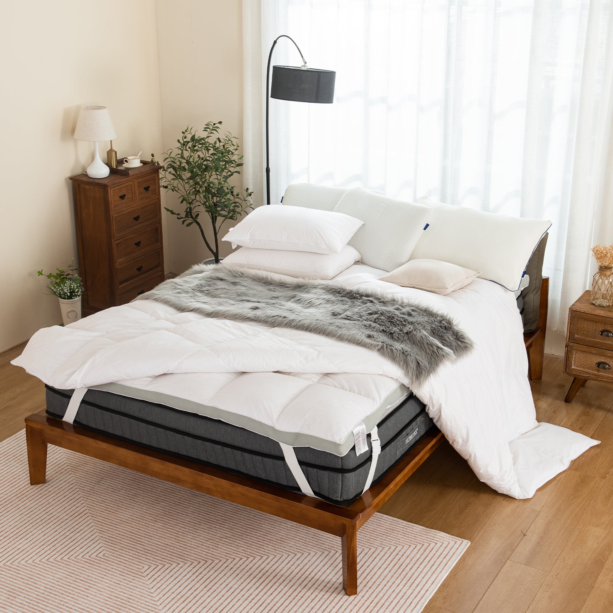 Bedroom set up with mattress and toppers with several bedding accessories